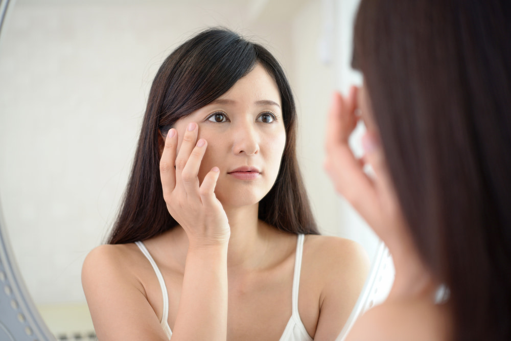 A woman looking in the mirror worried about face skin problems with age